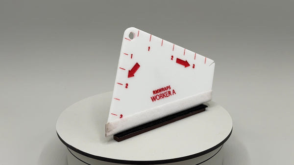 White triangular ruler with red markings and text on a gray background