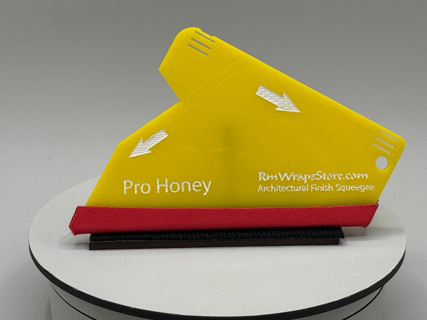 Yellow and red architectural finish squeegee on a white stand with a gray background