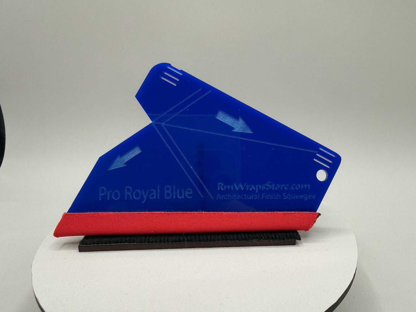 Blue and red squeegee on a white platform with a gray background