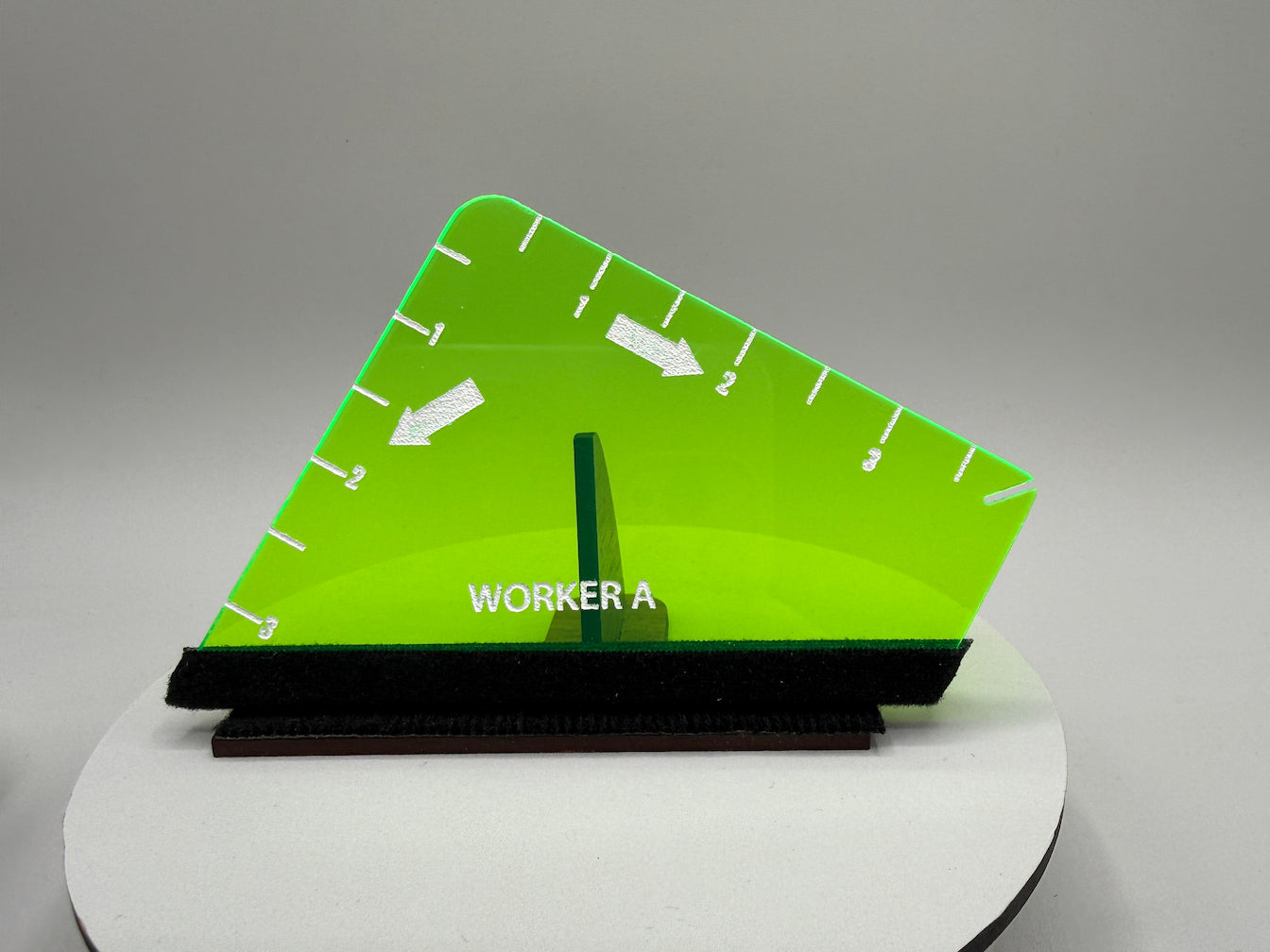 Green triangular ruler with measurement markings on a gray background