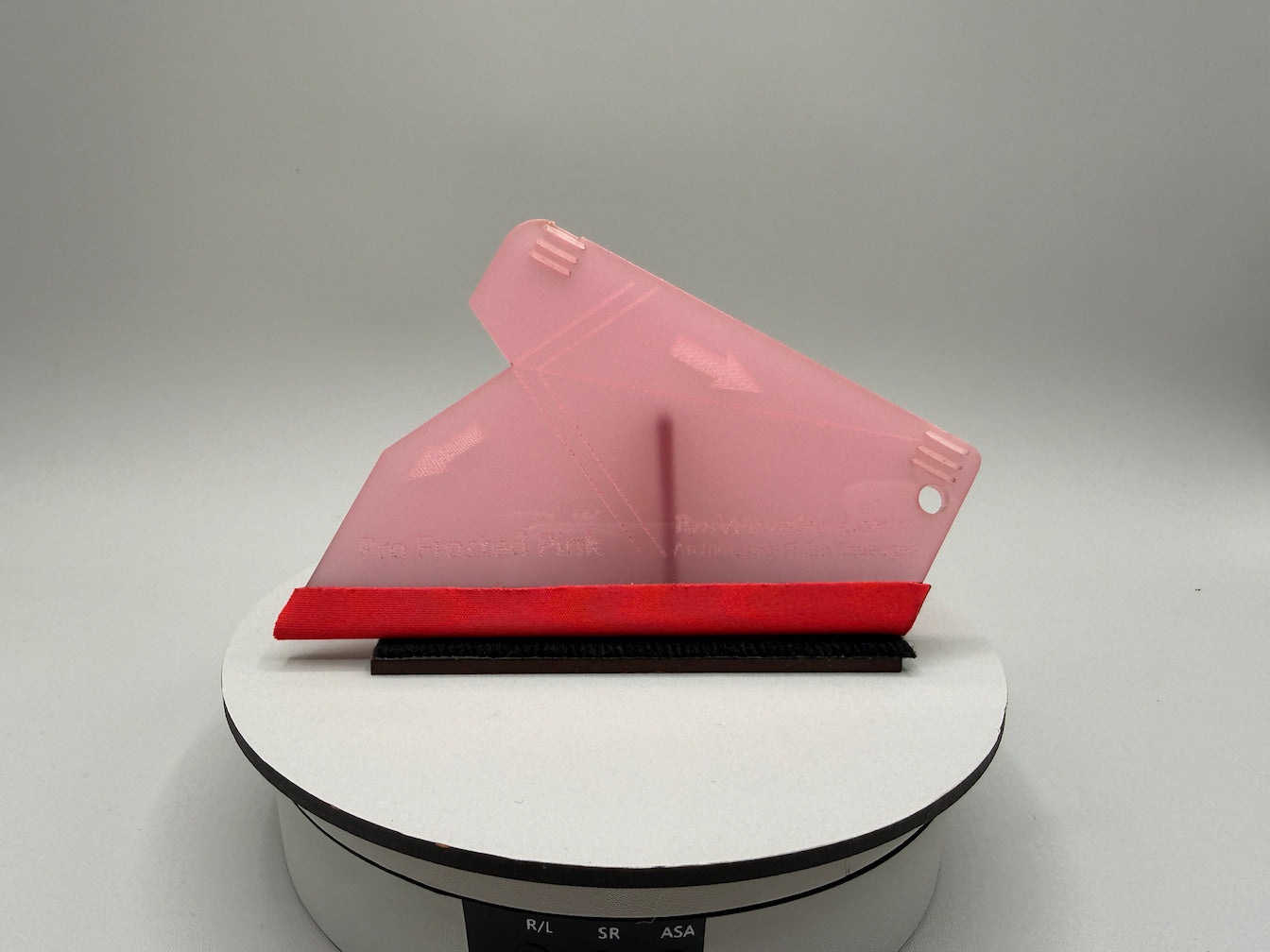 Pink and red object on a white platform with a gray background