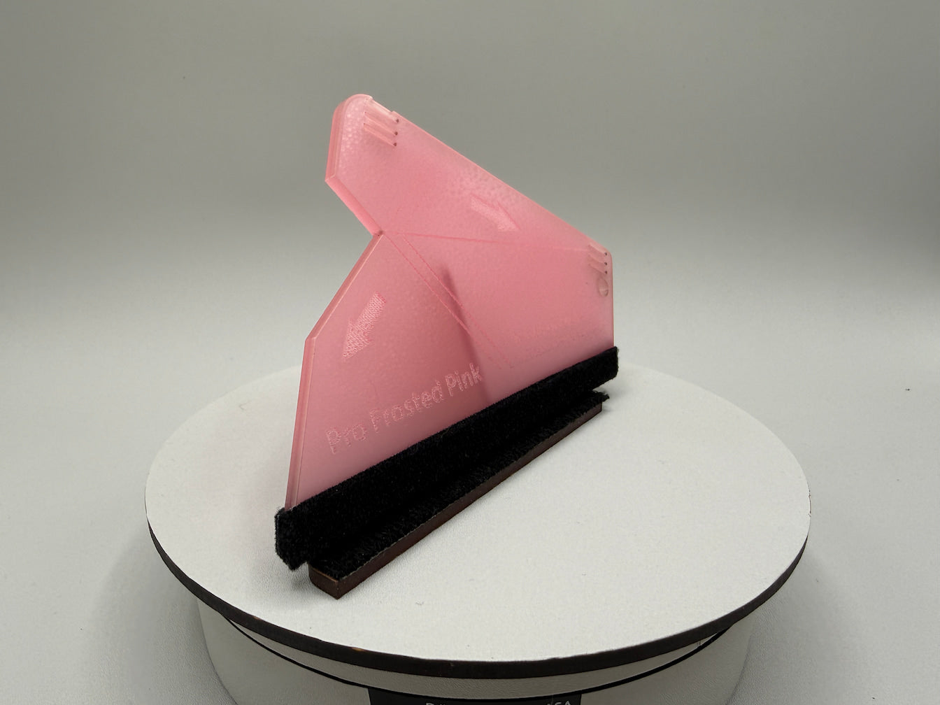 Pink squeegee on a white stand with a gray background