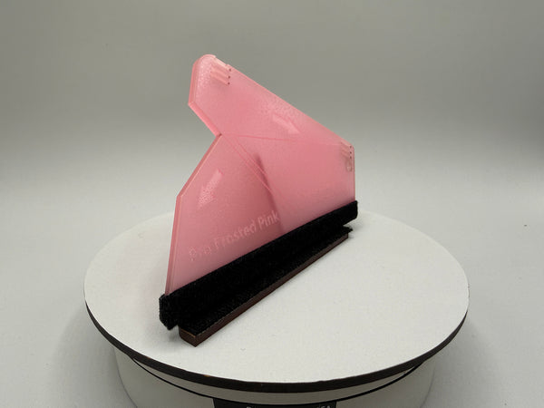 Pink squeegee on a white stand with a gray background