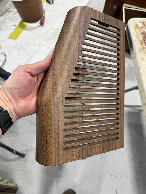 Hand holding a wooden air vent cover on a blurred background