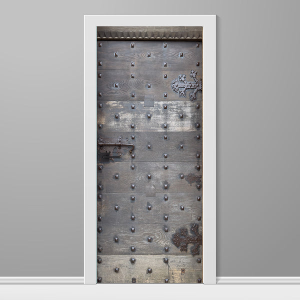 Decorative door with metal studs and a white frame on a gray wall.